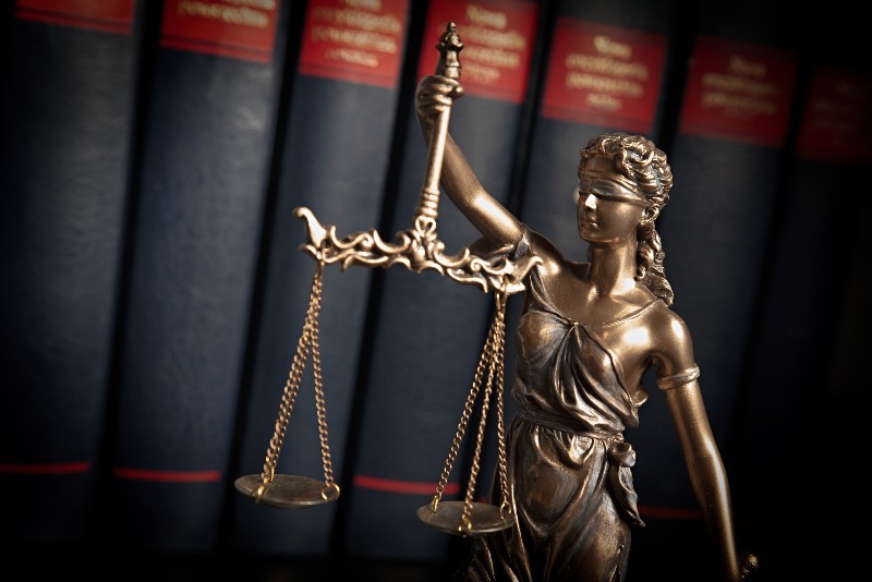 Lady Justice statue holding scales in front of law books by the Law Offices of Robert E. O’Connor